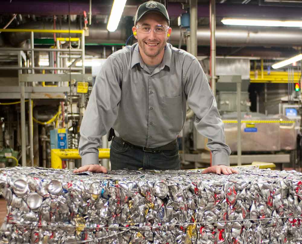 Employee standing behind crushed cans