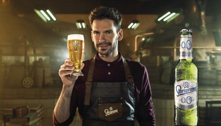 man holding glass of staropramen 0.0%