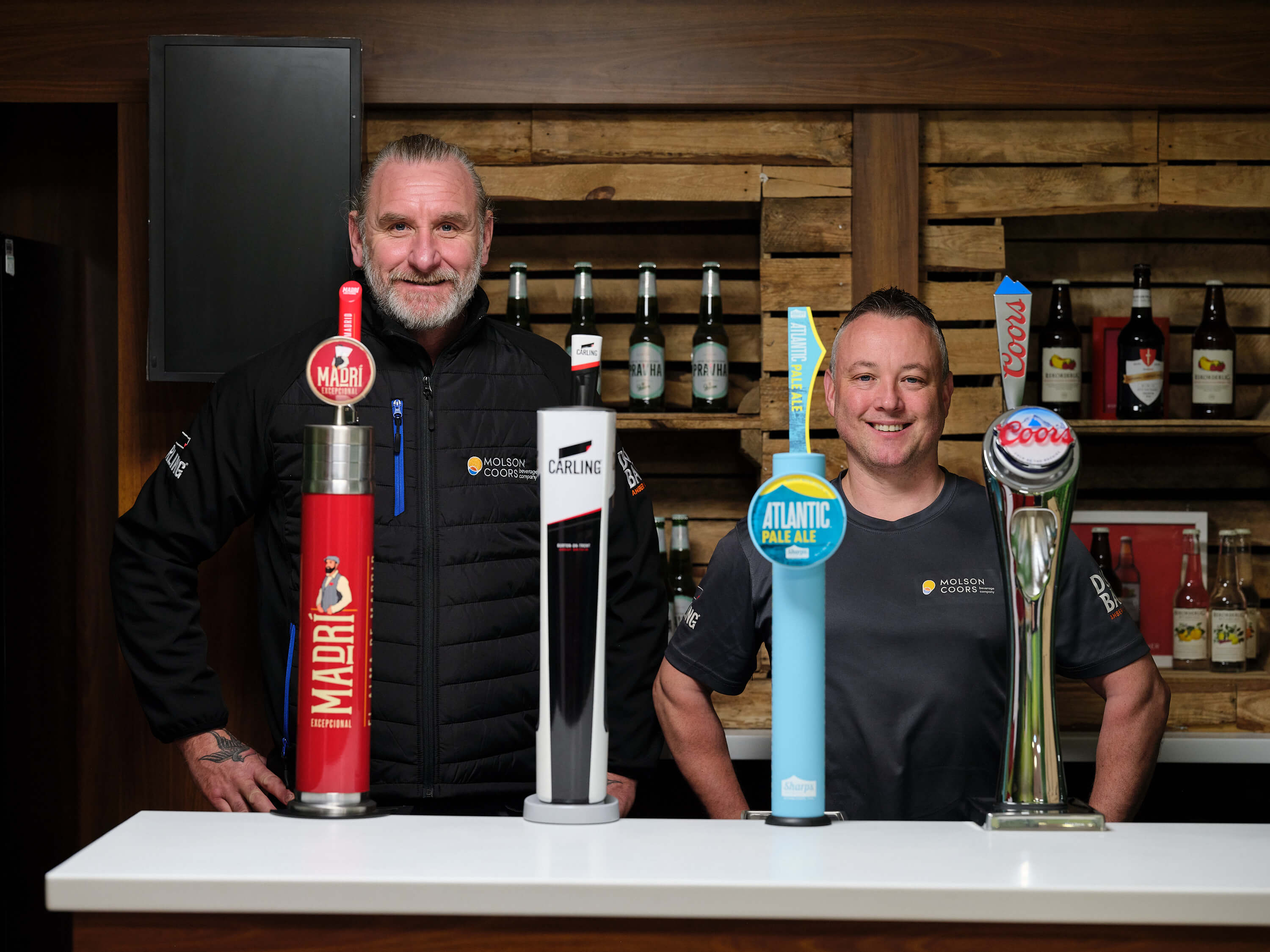 two man standing behind four molson coors dispense fonts